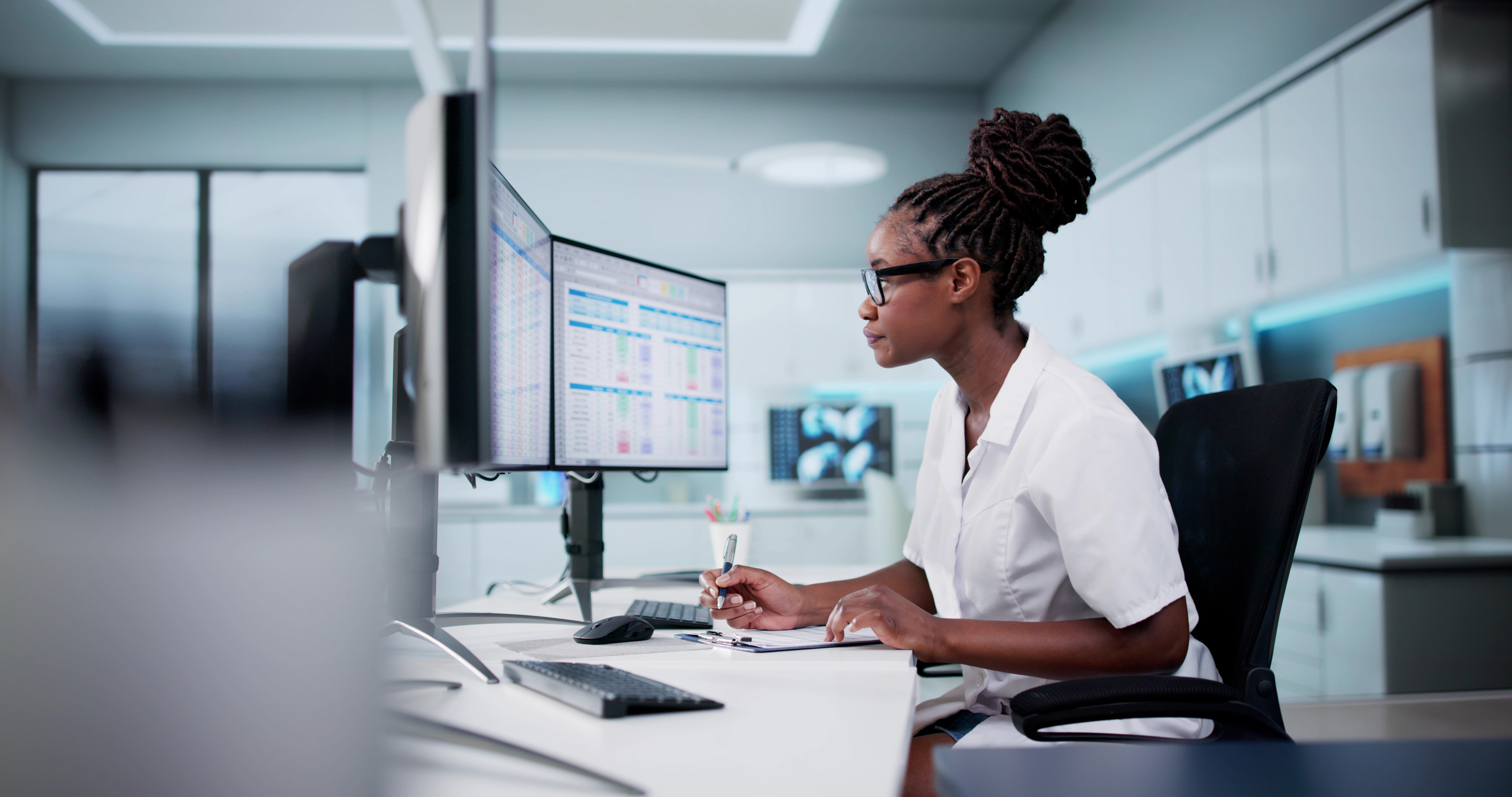 Dental professional working at computer with dual monitors